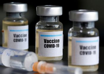 Dokumentasi - Botol kecil berlabel stiker "Vaksin COVID-19" dan jarum suntik medis