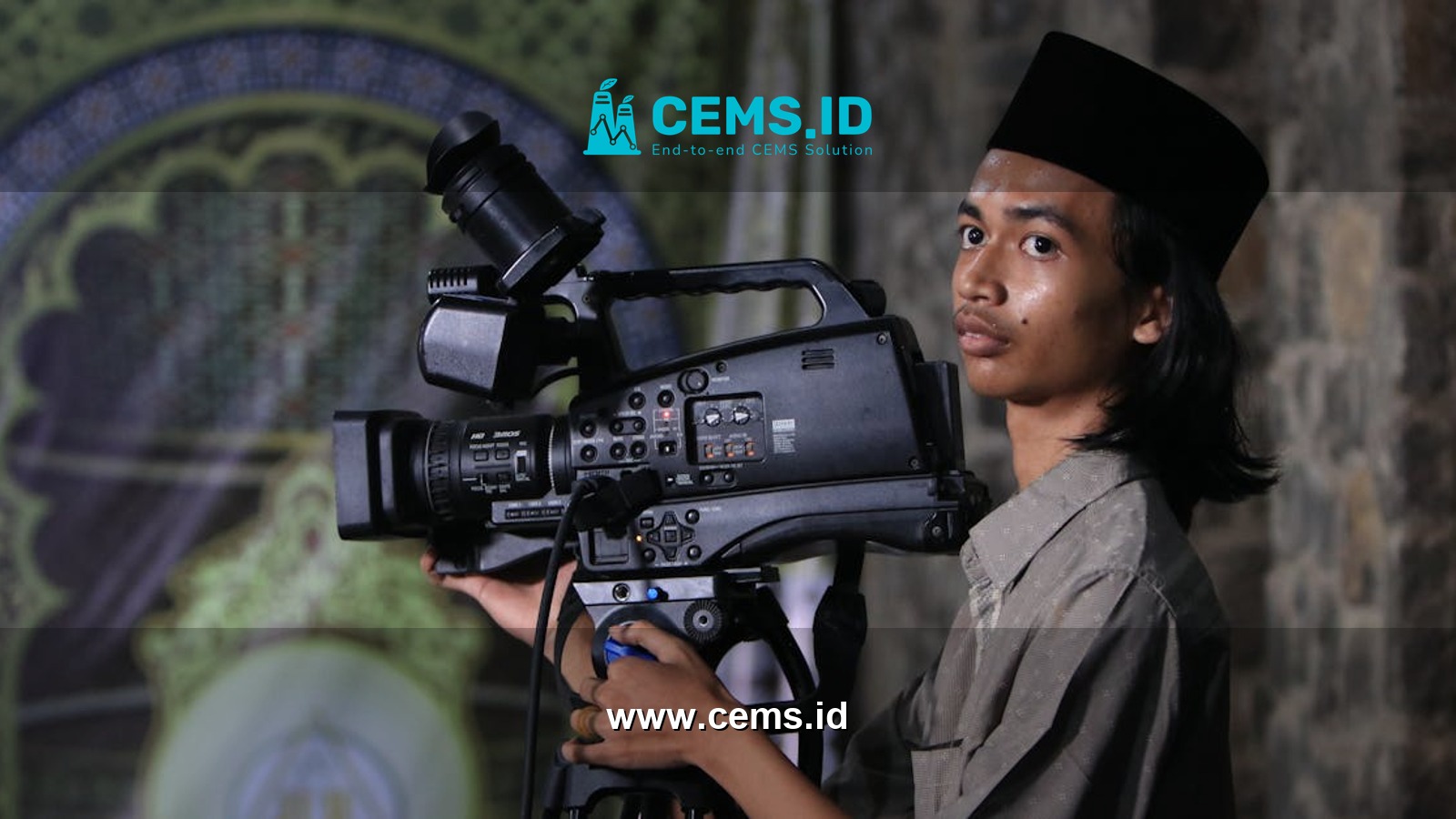 A young man operates a video camera indoors in Depok, Indonesia.