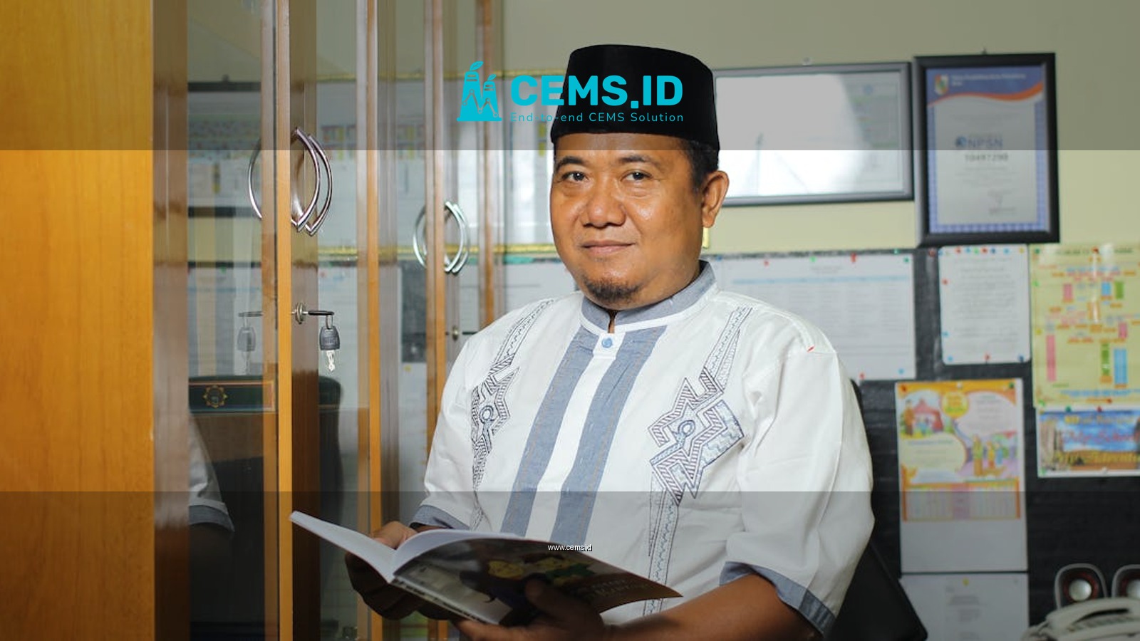 A teacher standing in an office in Indonesia, holding a book, conveying education.