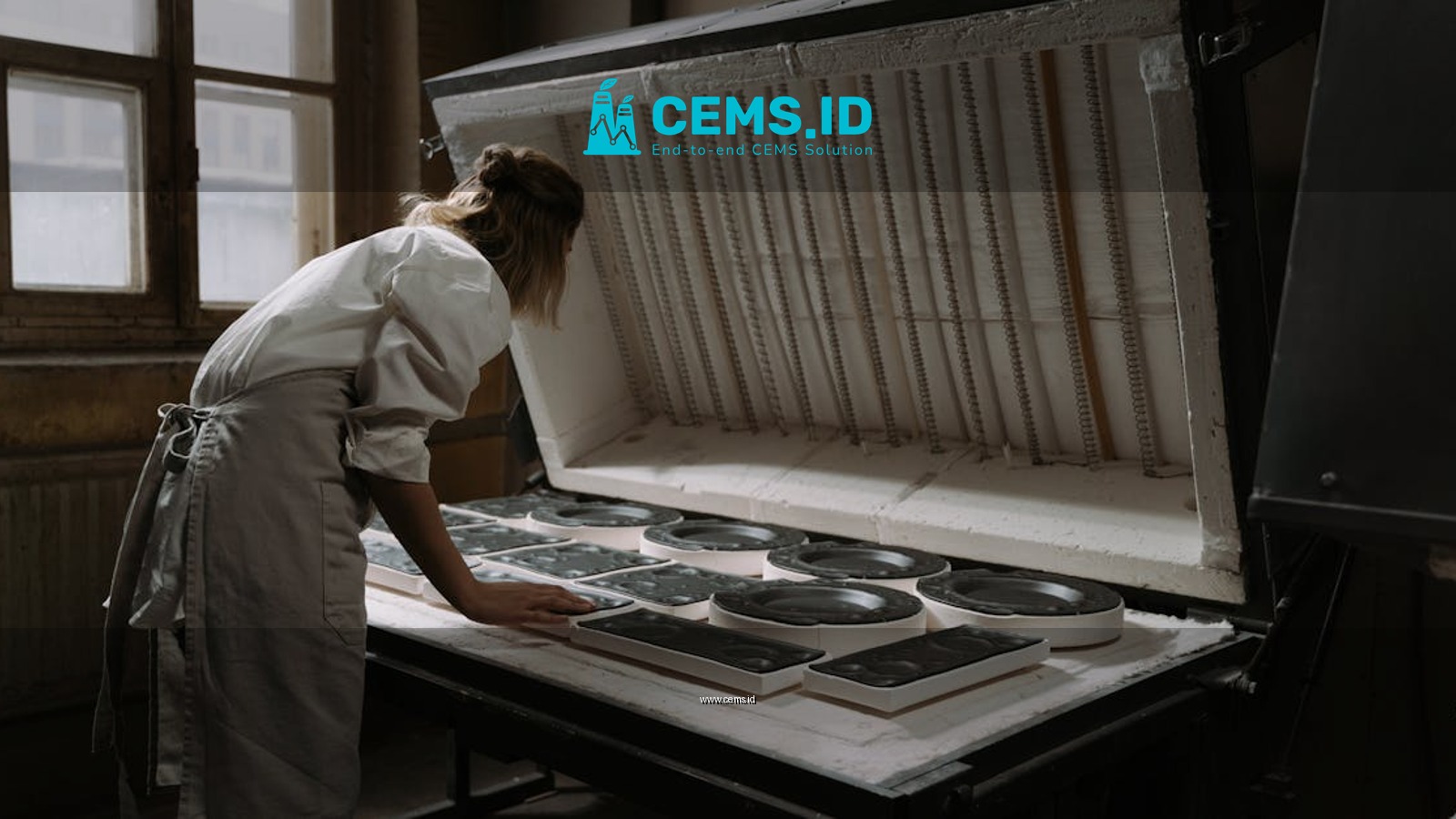 A female artisan carefully arranges ceramics in an industrial kiln, indicating precision and craftsmanship.
