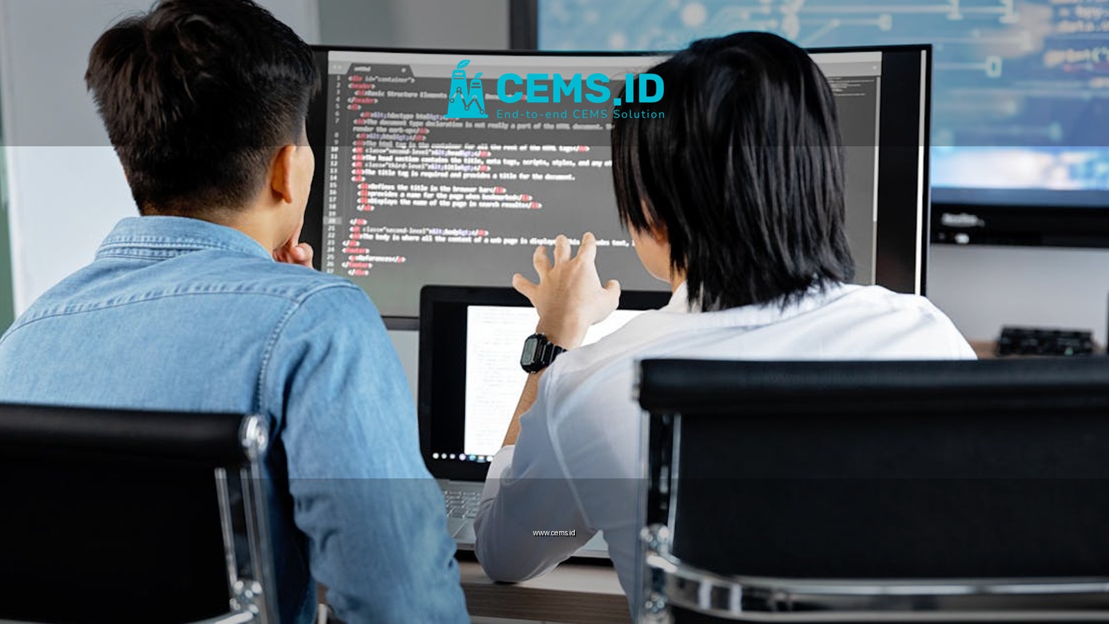 Two developers working together in an office, discussing code on a screen. Technology teamwork setting.