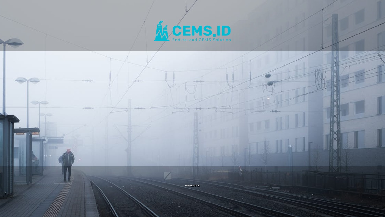 A solitary figure walks through a foggy train station, capturing a serene urban moment.