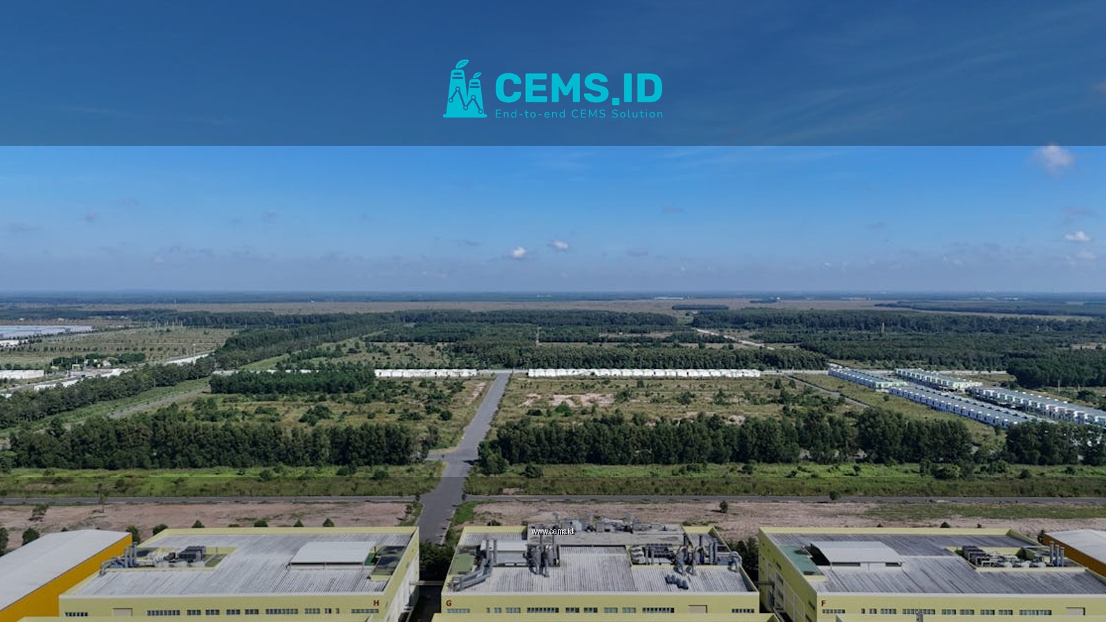 Aerial shot of industrial buildings and green landscape in Bình Dương, Vietnam under a clear blue sky.