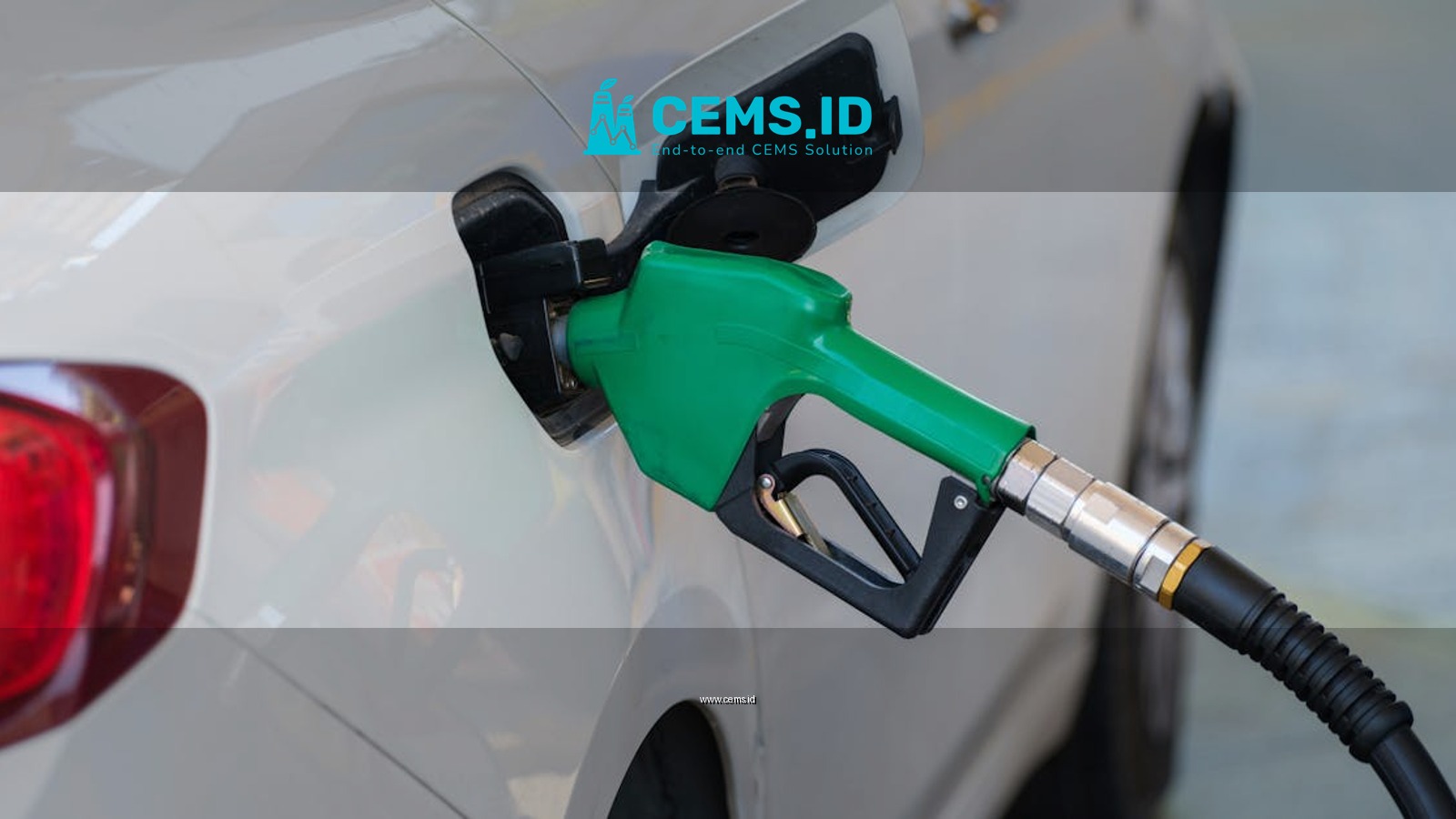 Close-up of a green nozzle refueling a white car at a gas station.