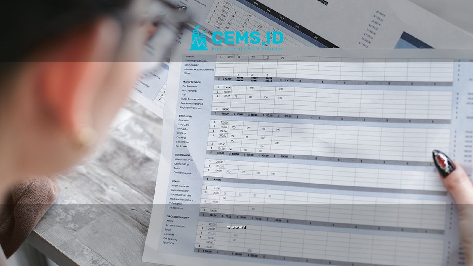 A businesswoman reviewing financial spreadsheets with charts and graphs in an office setting.