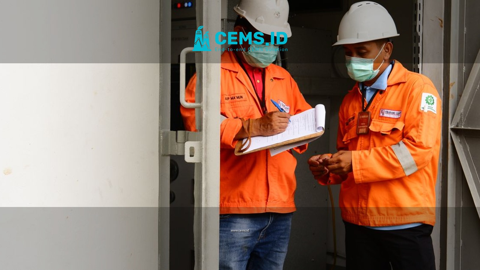 Two construction workers in safety gear discussing plans at a site entrance.