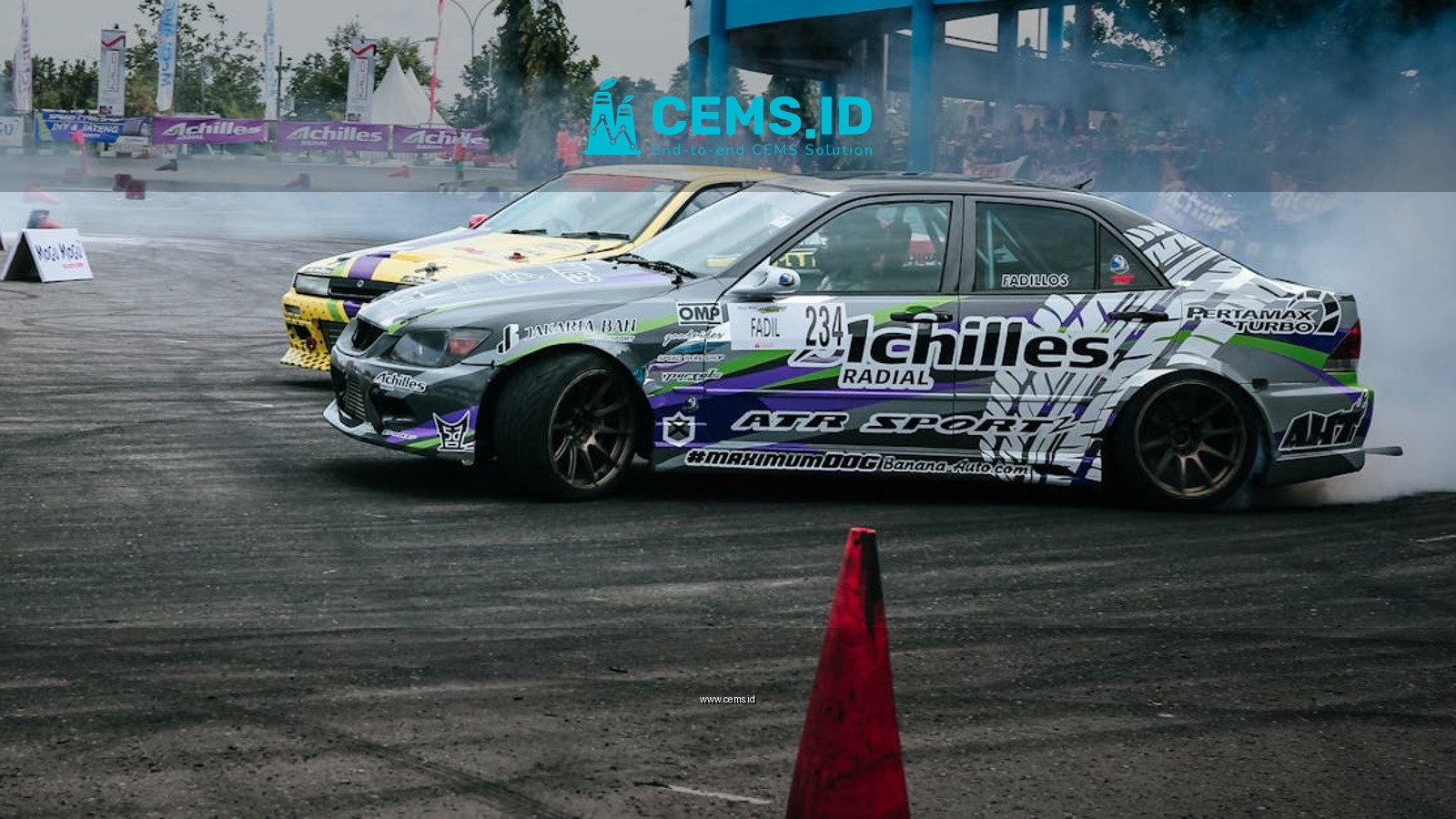 A thrilling scene of cars drifting on a speedway, showcasing motorsport action.