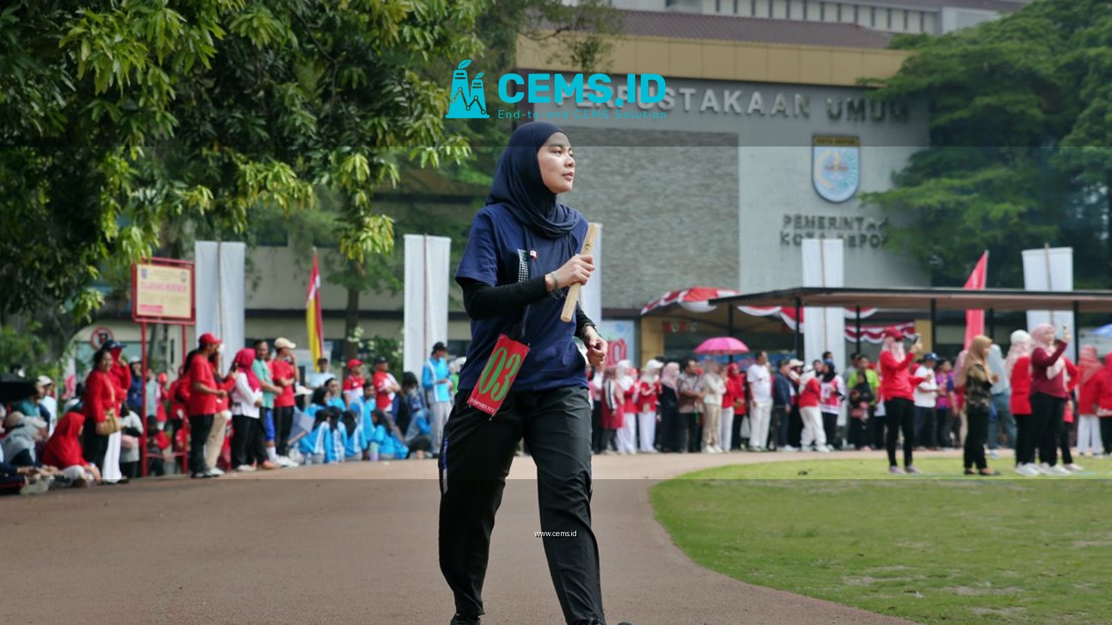 A young woman walking confidently at a lively community event held outdoors, with a crowd in the background.