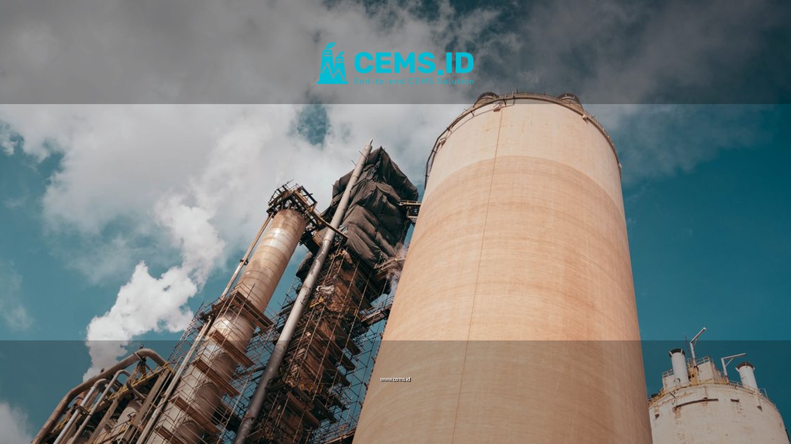 Industrial factory towers emit smoke against a vibrant blue sky, highlighting environmental concerns.