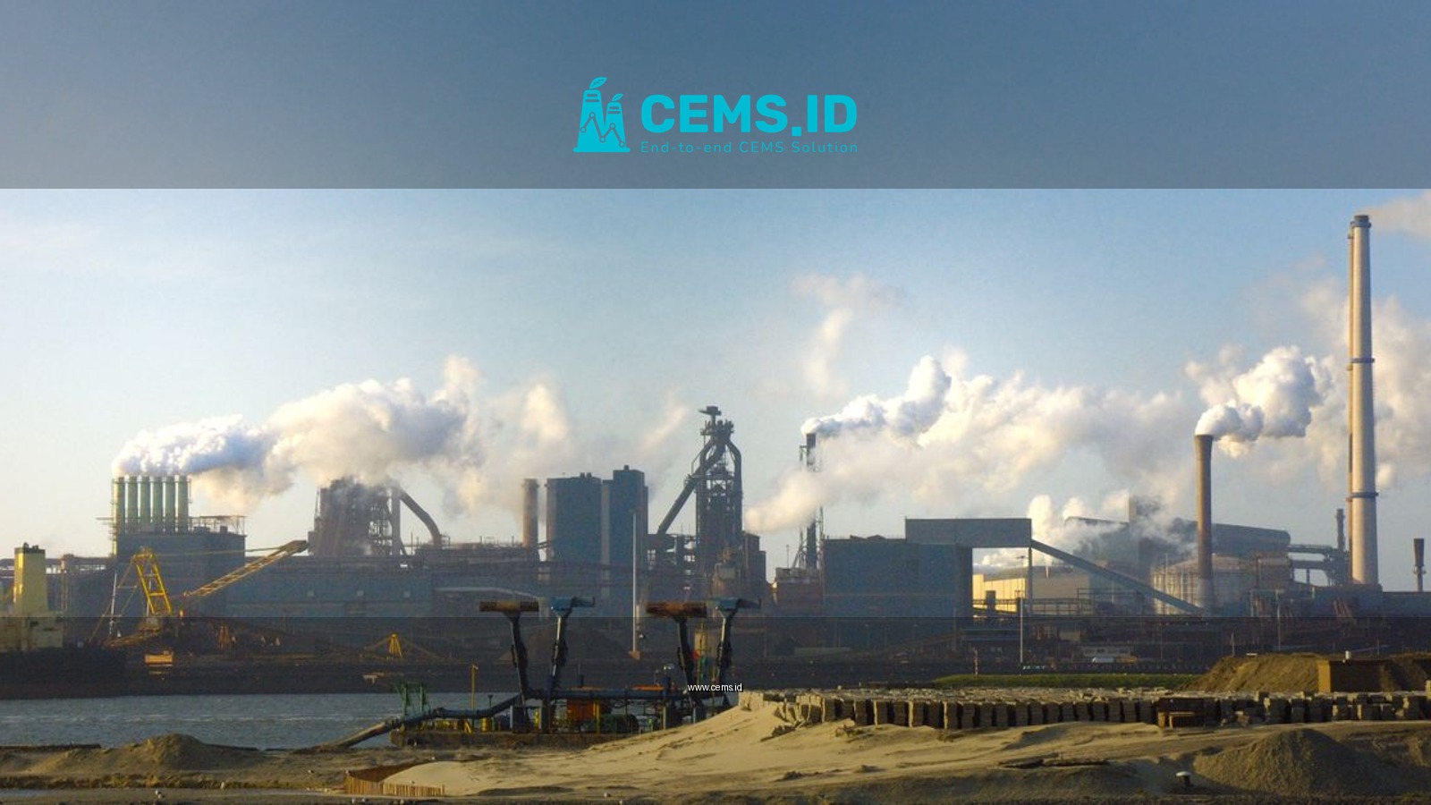 View of the steel plant in IJmuiden, Netherlands with smoke pollution against a clear sky.