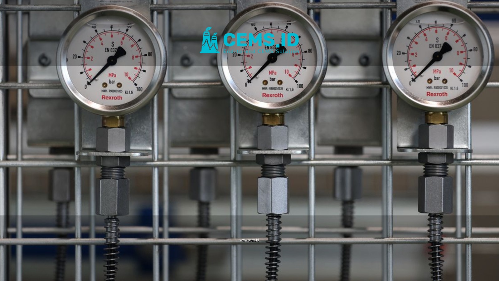 Close-up of industrial pressure gauges mounted on a metal grid in a factory setting.