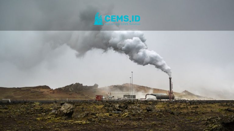 A large chimney releases smoke in the rural countryside, illustrating industrial activity.