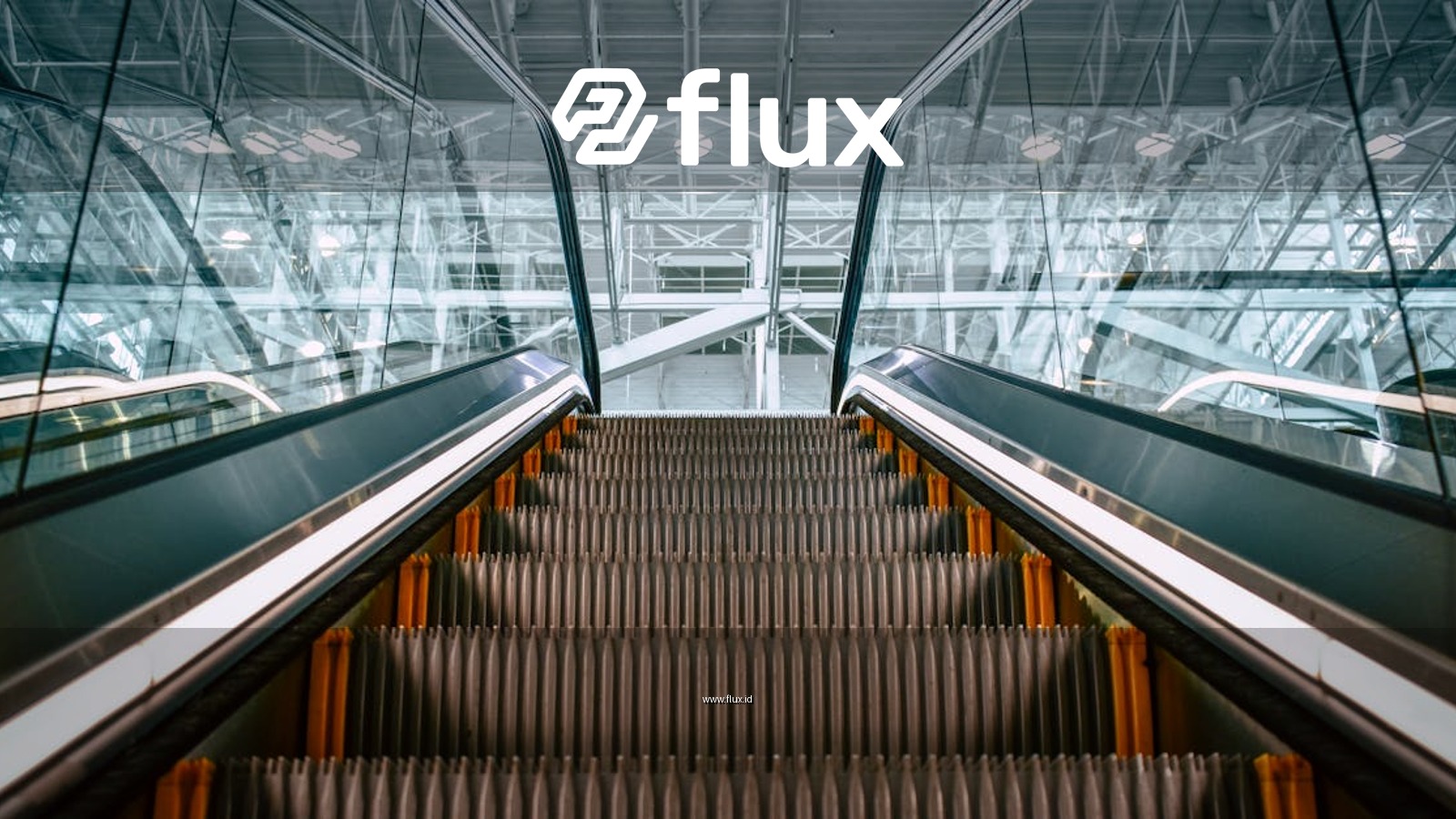 Low angle shot of a modern escalator inside a building, featuring steel framework and glass panels.