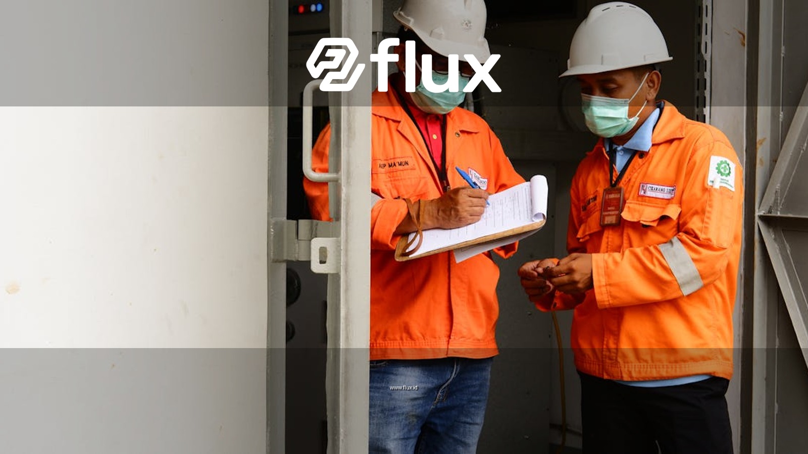 Two construction workers in safety gear discussing plans at a site entrance.