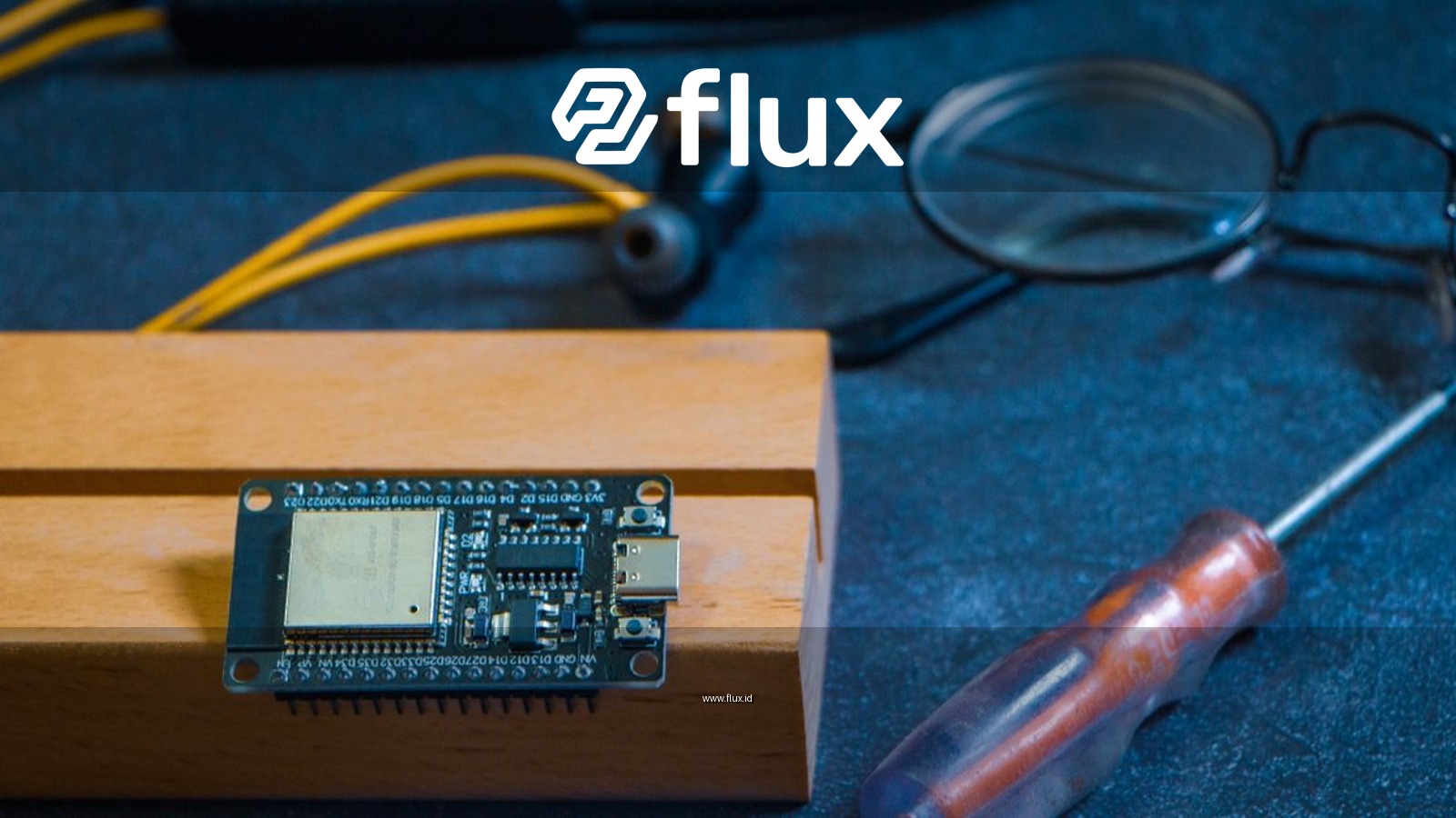 Close-up of an Arduino circuit board on a workshop table with tools and gadgets, showcasing DIY electronics.