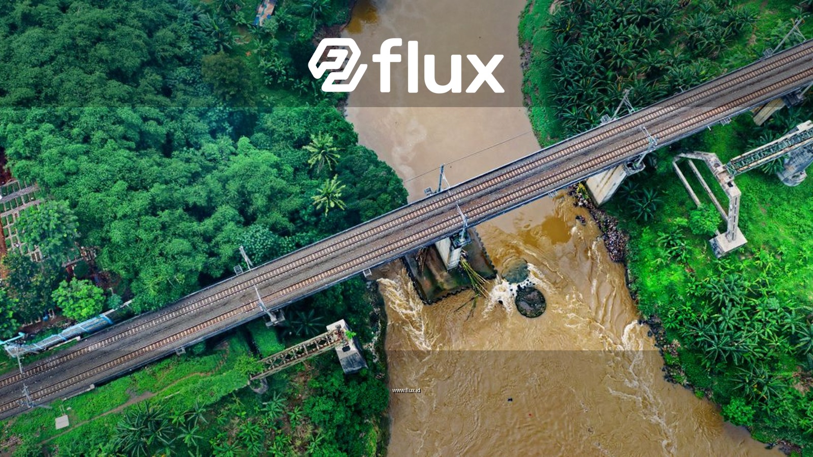 Aerial view of a railway bridge crossing a lush river in Sindang Jaya, Indonesia.