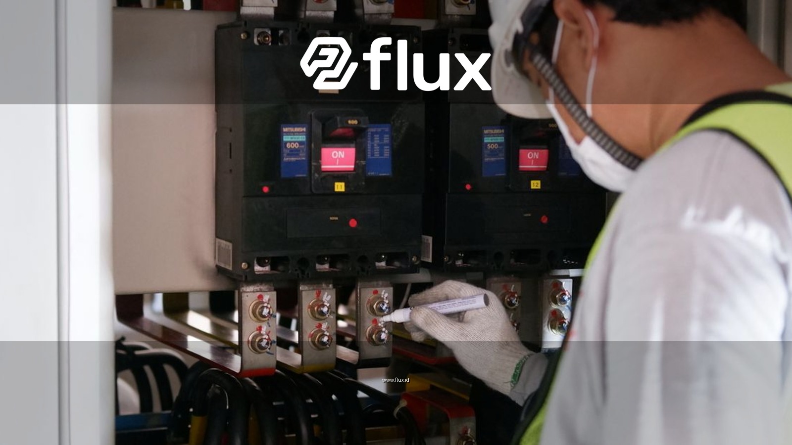 Technician wearing safety gear inspecting electrical panels in an industrial setting.