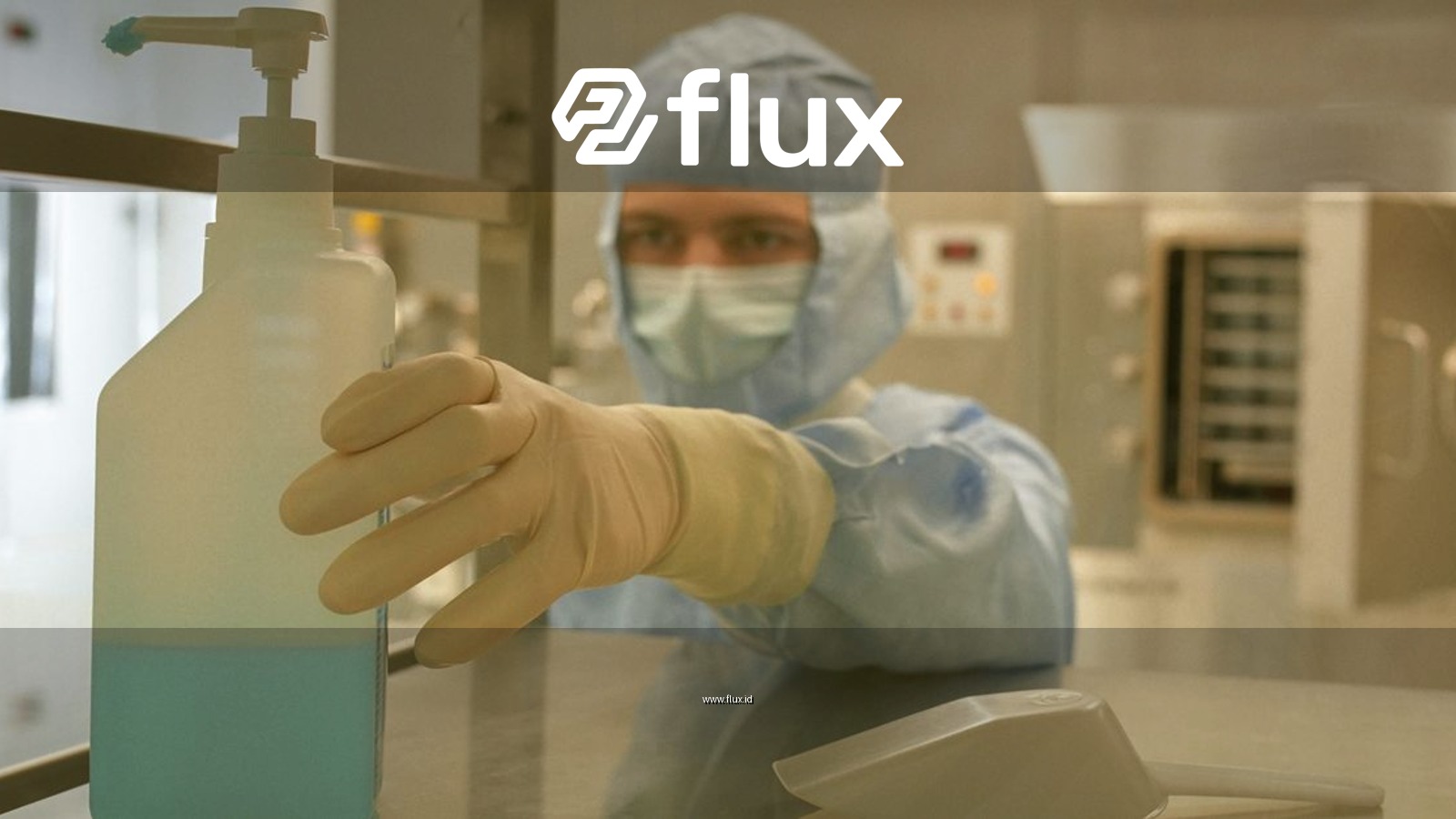 A scientist in protective gear reaching for a sanitizer bottle in a laboratory setting.