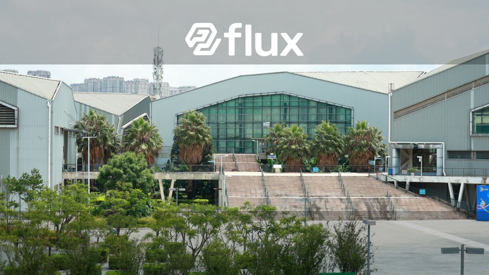 Exterior view of an industrial building surrounded by lush greenery on a sunny day.