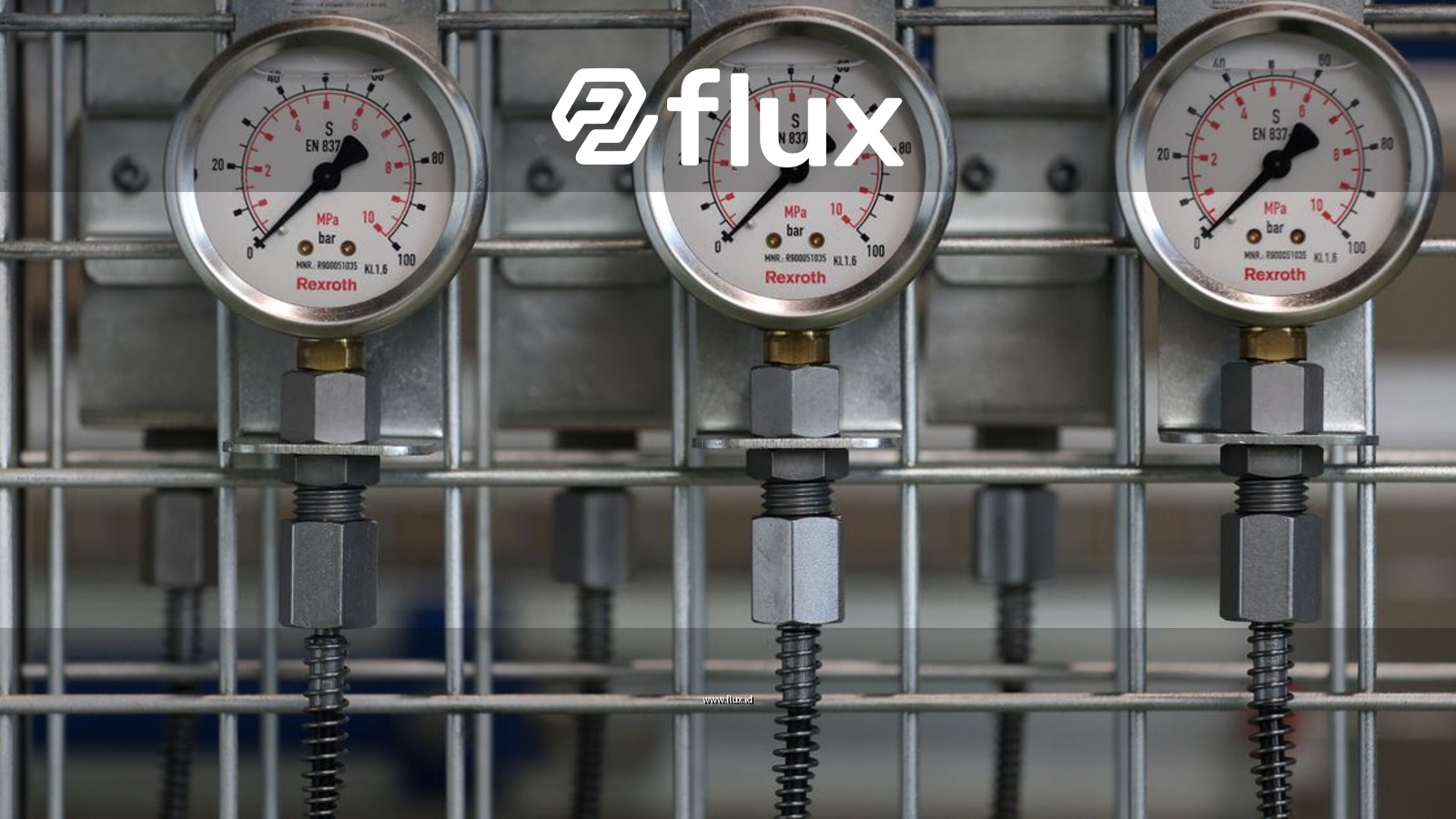 Close-up of industrial pressure gauges mounted on a metal grid in a factory setting.