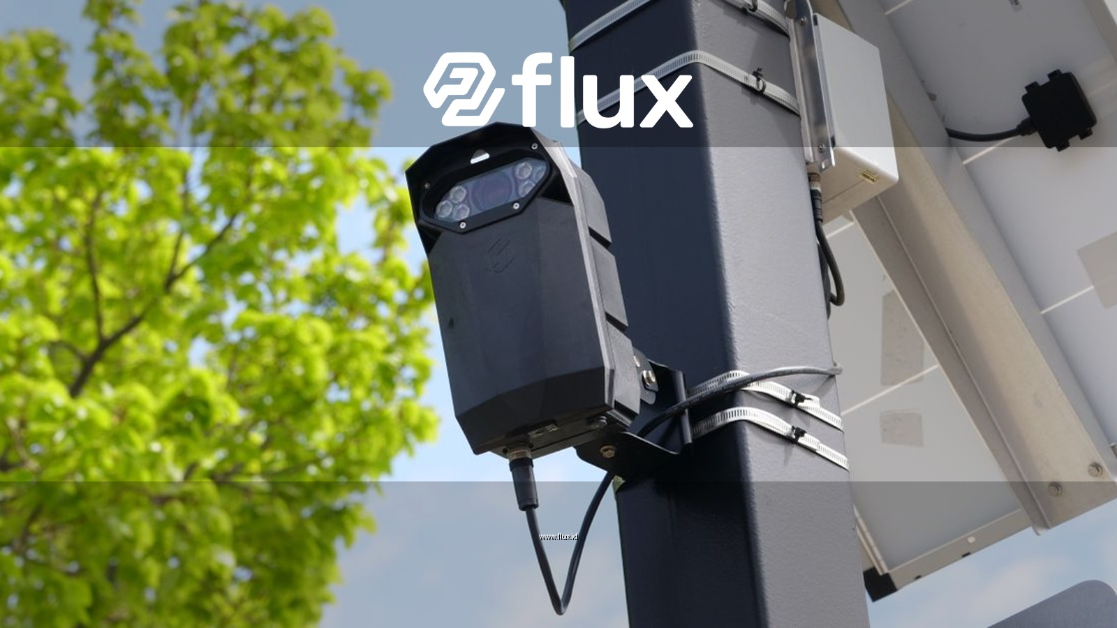 A modern surveillance camera powered by solar energy mounted on a street pole.