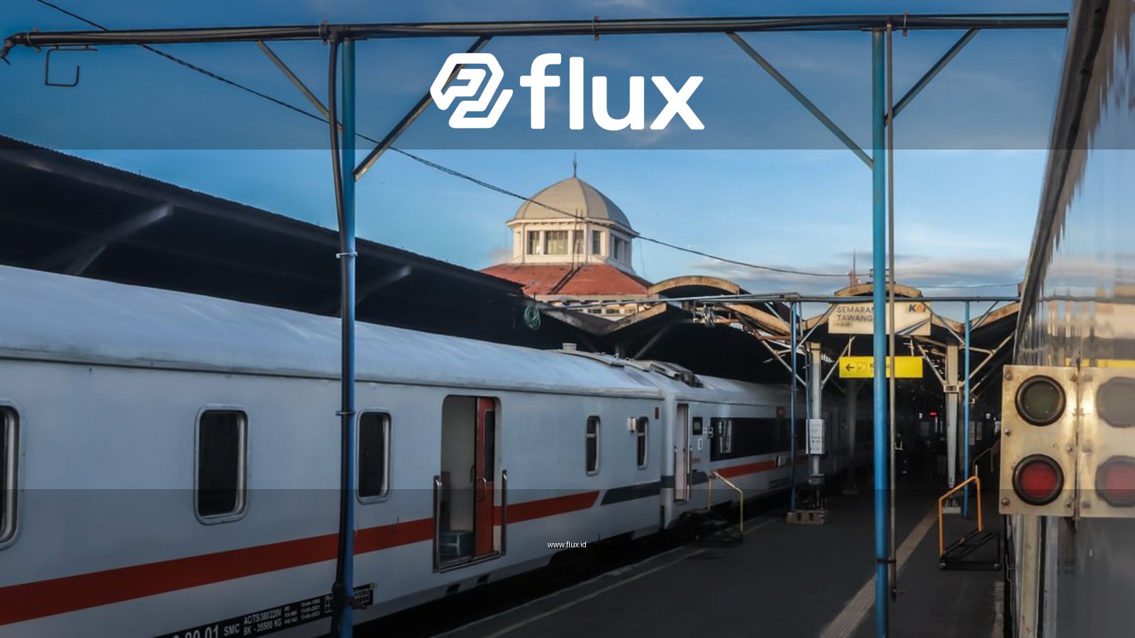 A train station with white passenger trains and a blue sky backdrop.
