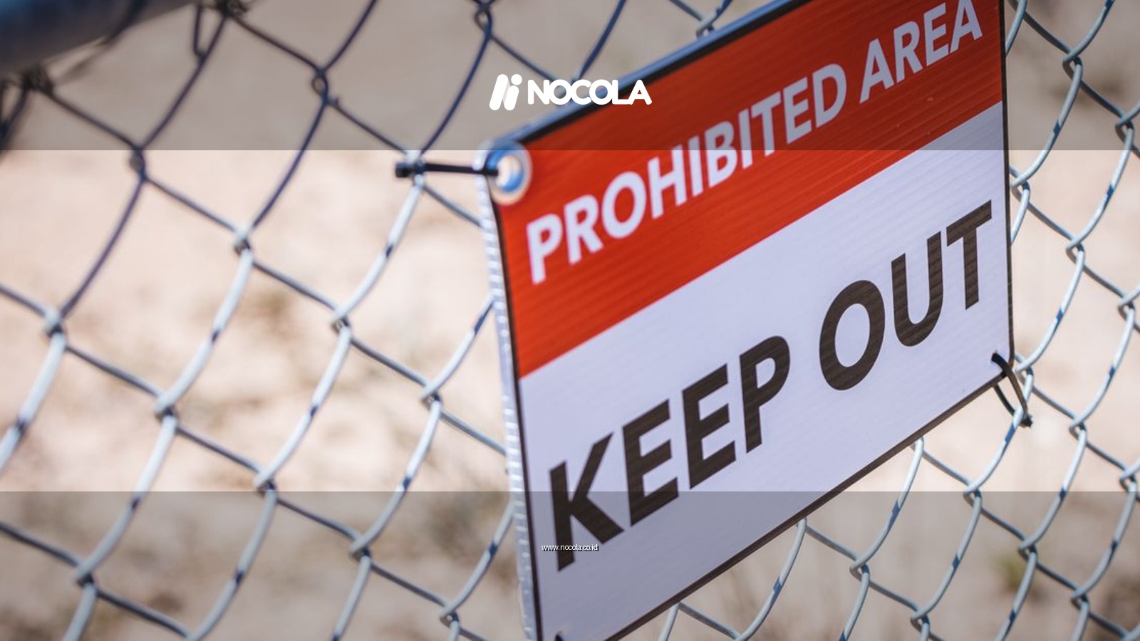 Close-up of a 'Prohibited Area' and 'Keep Out' sign on a chain link fence.