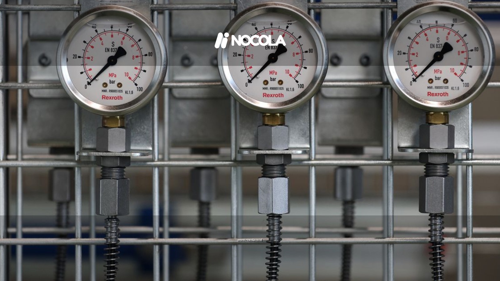 Close-up of industrial pressure gauges mounted on a metal grid in a factory setting.
