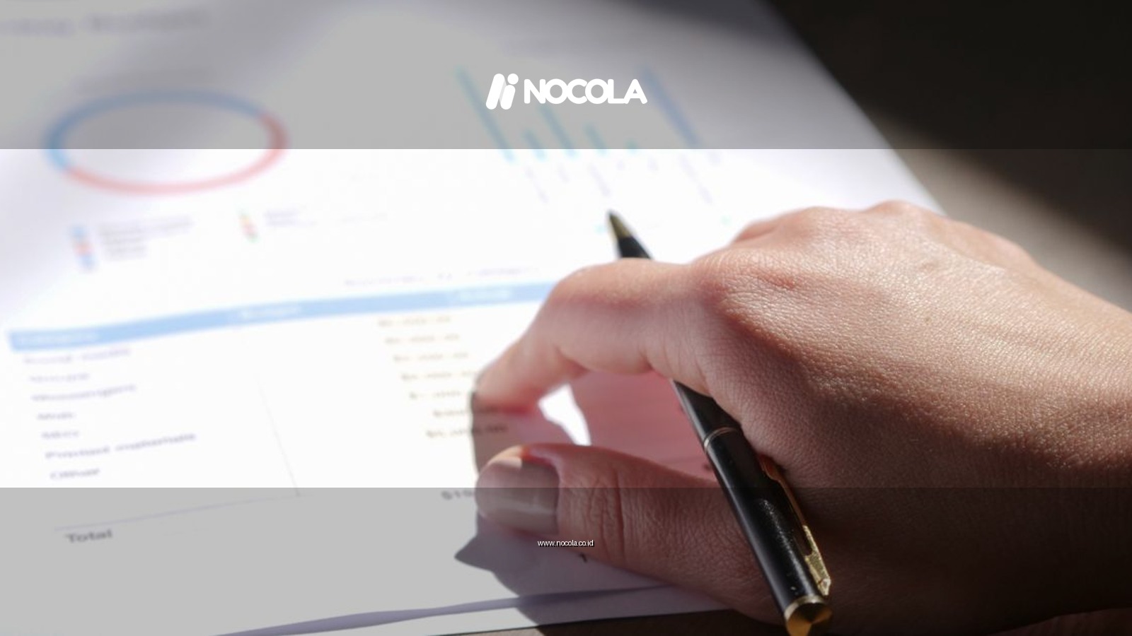 A close-up view of a hand holding a pen and examining financial charts on paper.