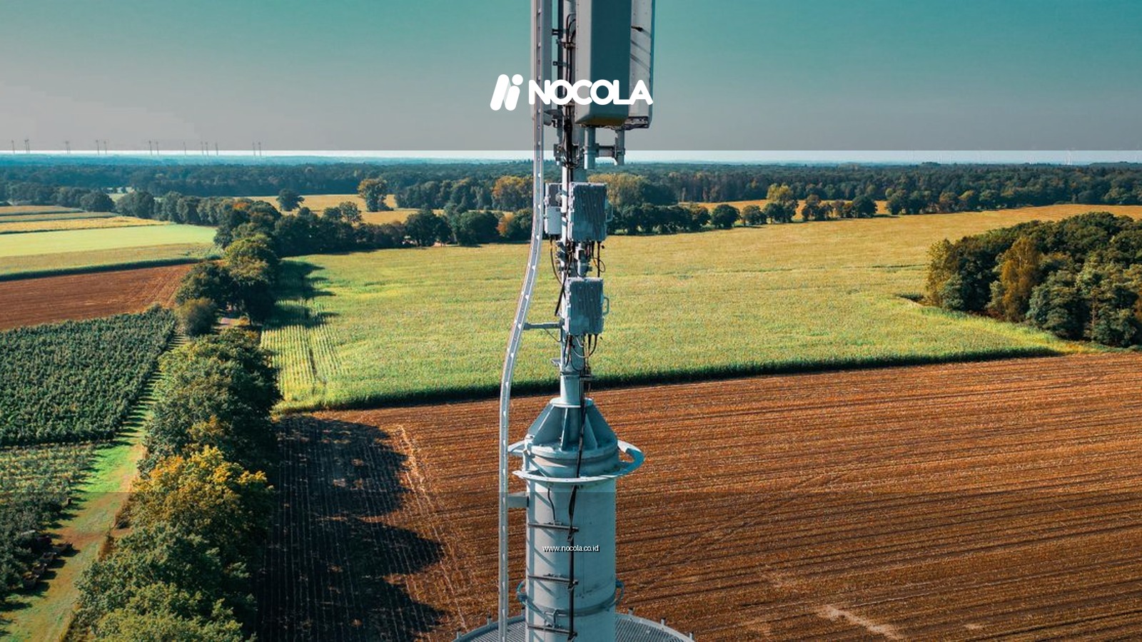 Aerial view of a cell tower amidst vibrant farmland, symbolizing technology and nature coexistence.