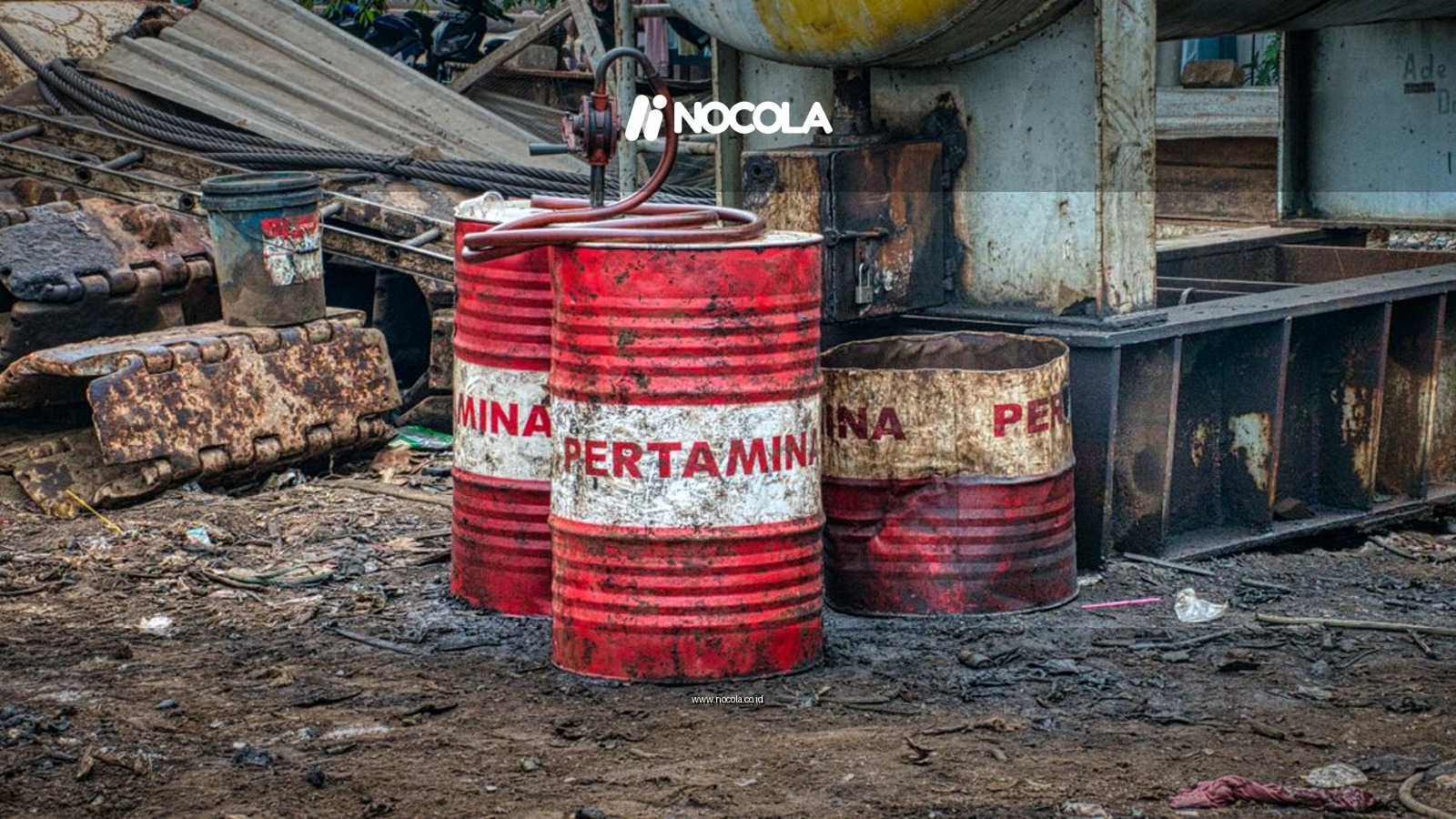 Old red metal barrels with inscription placed on ground in landfill in daylight