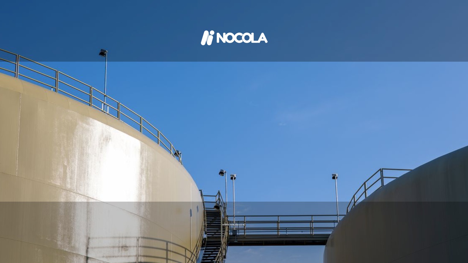 Sunlit industrial silos connected by a staircase under a clear blue sky.