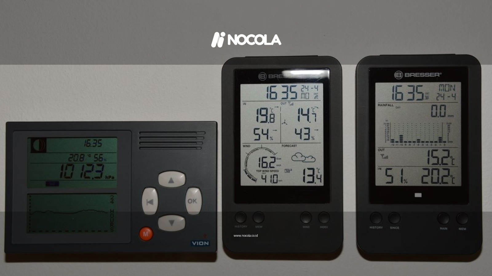 Multiple digital weather monitors on a wall displaying temperature and pressure.