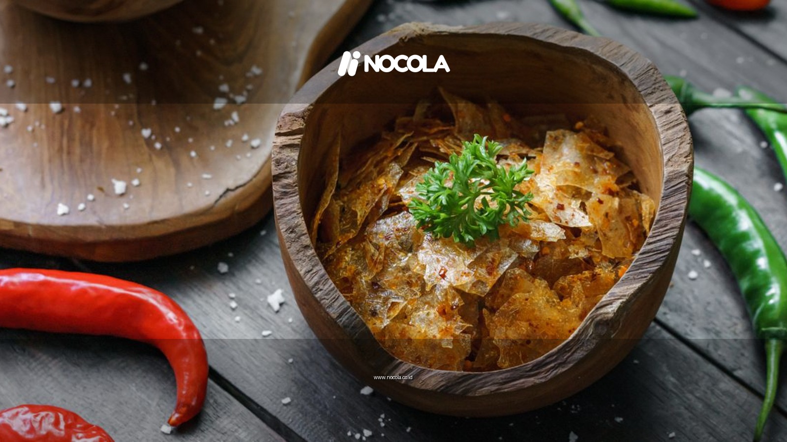 Crunchy Indonesian chips keripik kaca in a wooden bowl, accompanied by fresh red and green chilies.