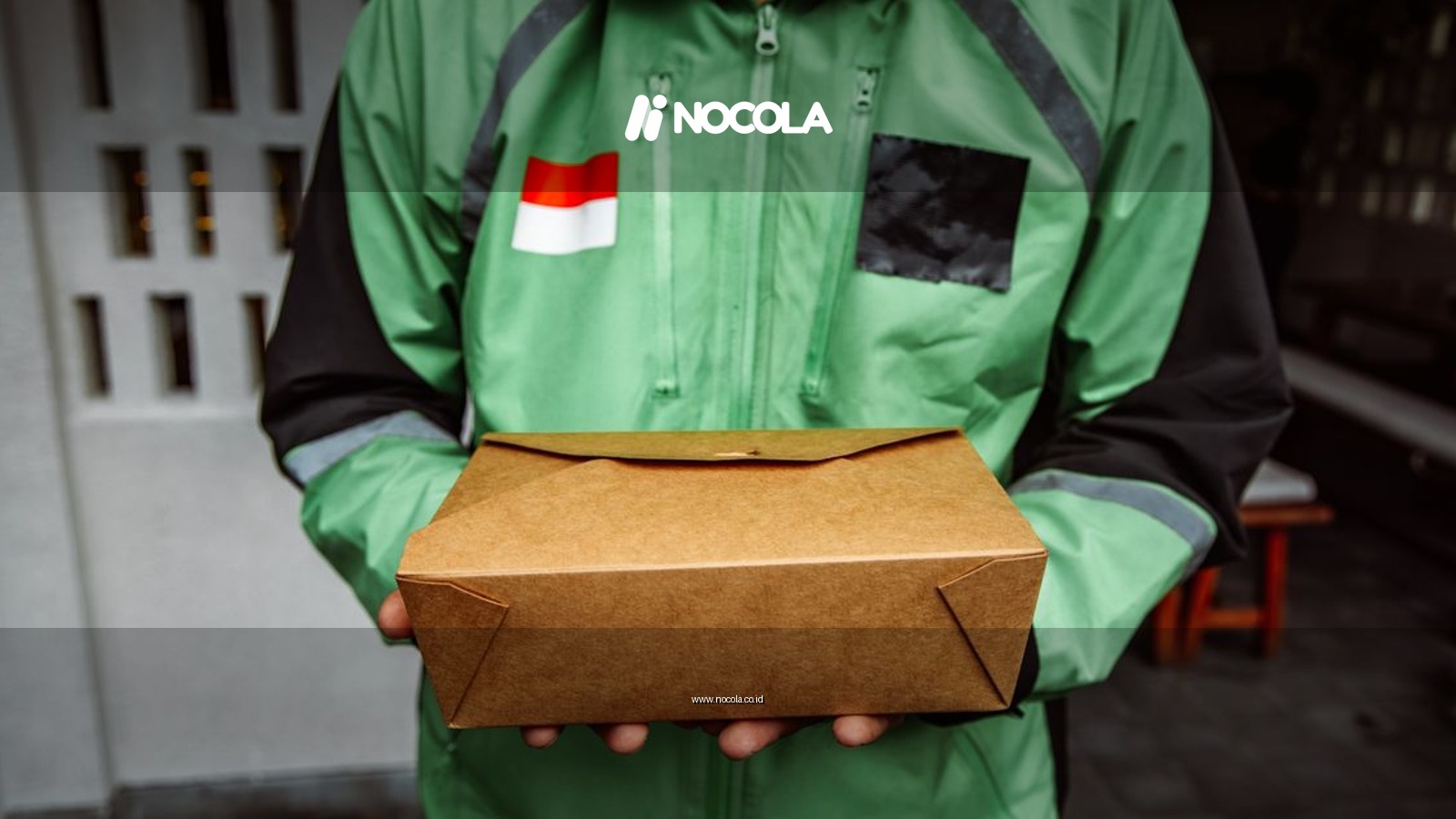 A delivery person in a green jacket holding a cardboard package outdoors.
