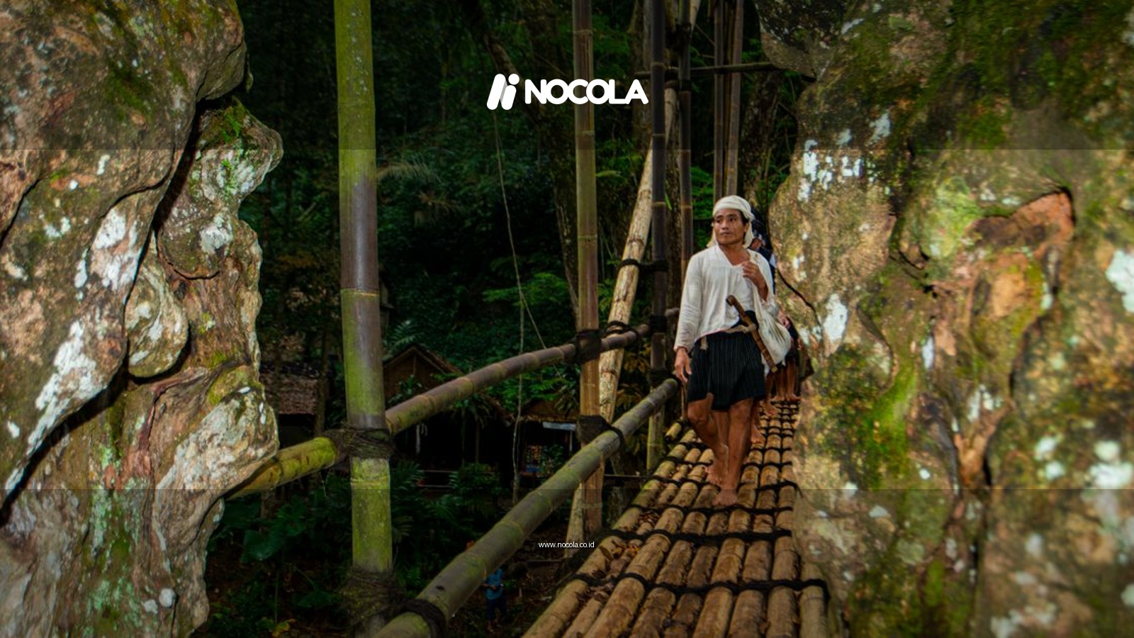 A person walks on a rustic bamboo bridge in the traditional Baduy village, Banten, Indonesia.