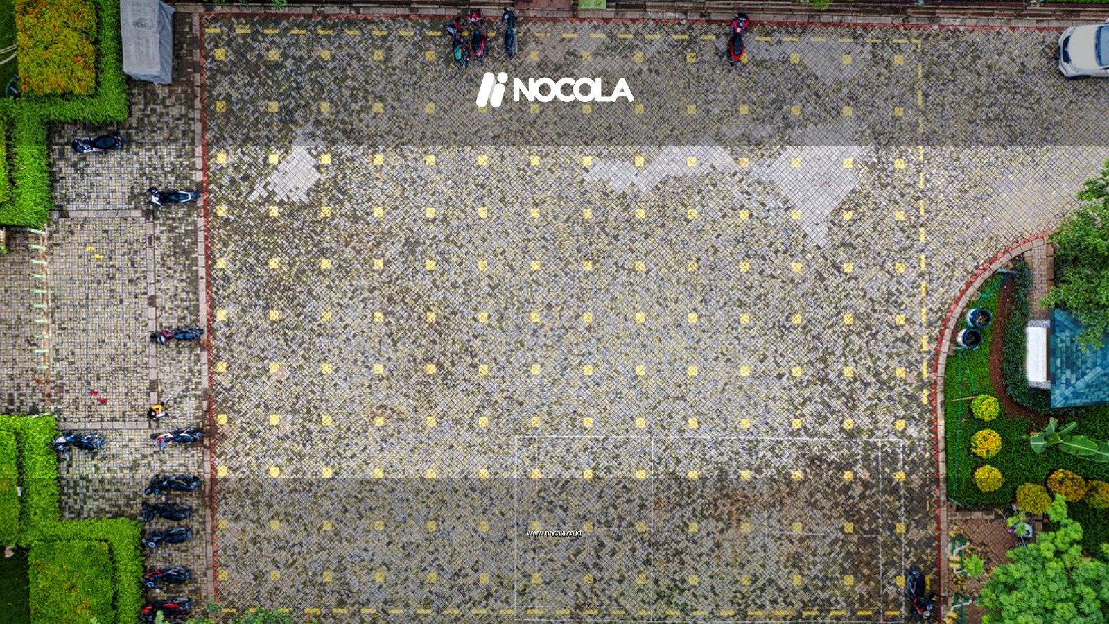 Top-down view of a parking lot surrounded by greenery in Jakarta, Indonesia.