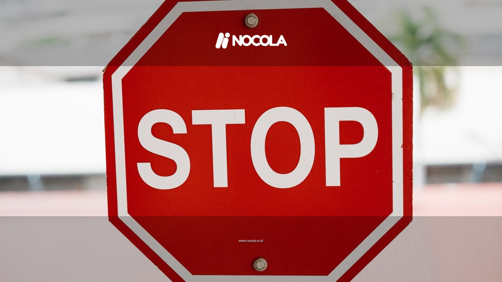 A red stop sign with bold white text in an urban setting, signaling caution.