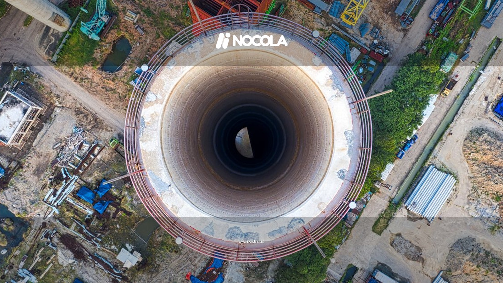 Aerial perspective of a cooling tower in an industrial area, highlighting complex machinery and structures.