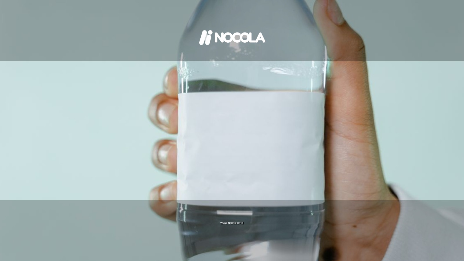 A clear plastic water bottle with blank label being held by a hand against a light background.
