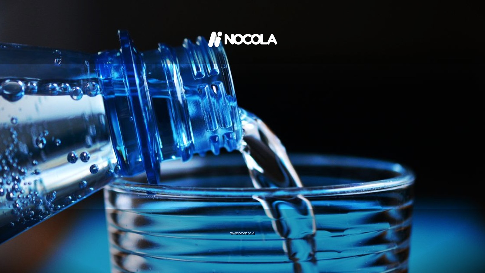 Close-up of sparkling water being poured from a bottle into a glass with bubbles visible.