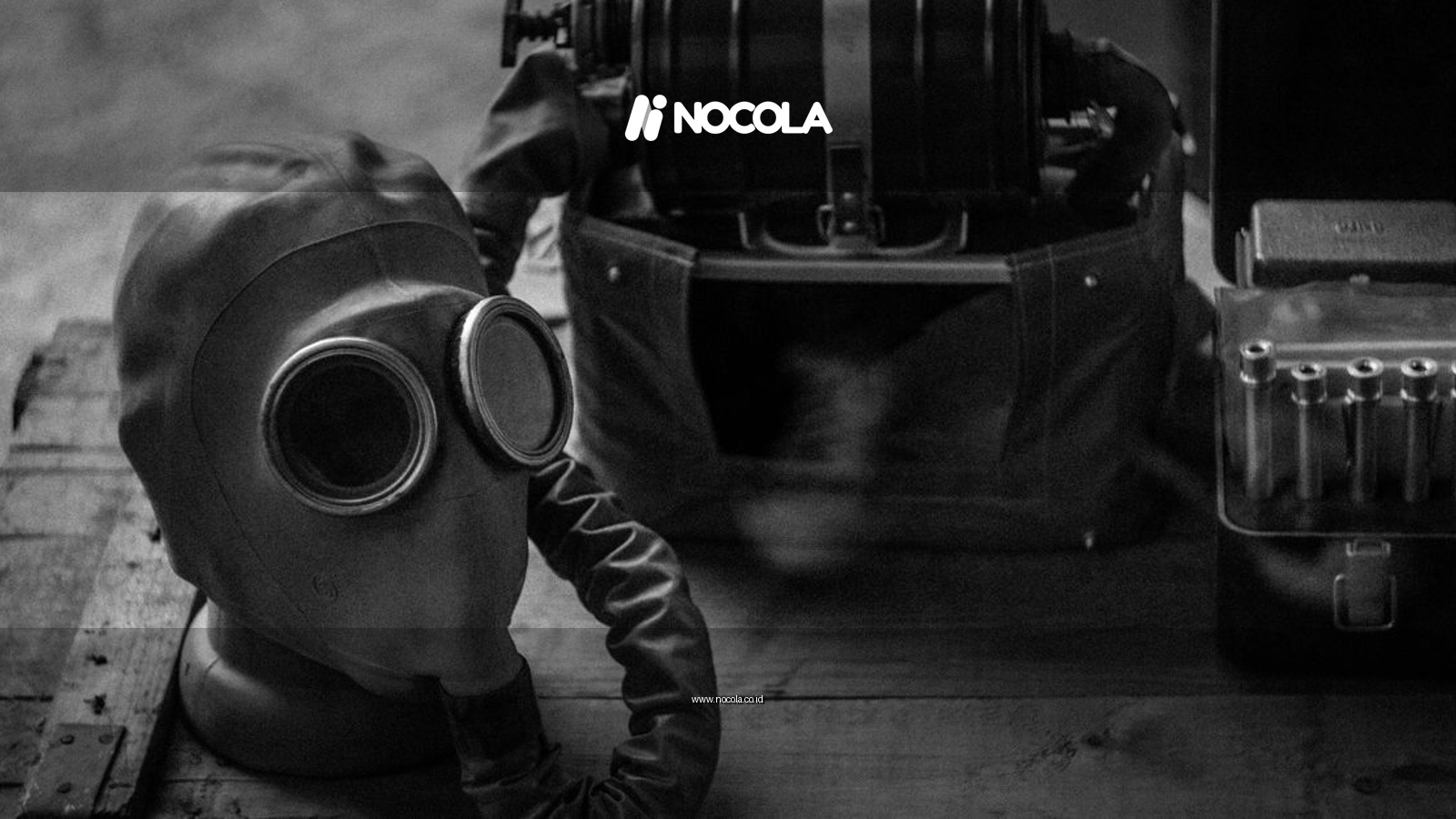 Black and white photo of a vintage gas mask and equipment on a wooden box.