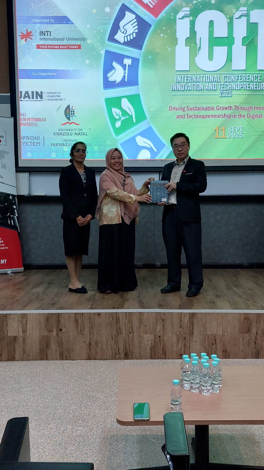 Dr.Tisha sedang menerima cendera mata dari Prof. Wong Ling Shing didampingi oleh Ketua Panitia, AP. Dr.Rajemani Thinakaran