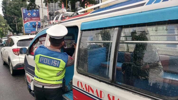 Personil Sat Lantas menempelkan stiker Himbauan tertib berlalulintas