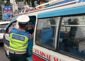 Personil Sat Lantas menempelkan stiker Himbauan tertib berlalulintas