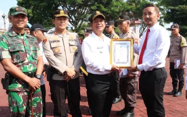 Bupati Simalungun Radiapoh Hasiholan Sinaga saat menyerahkan piagam penghargaan kepada Kasat Reskrim Polres Simalungun, AKP Racmat Aribowo (ist)