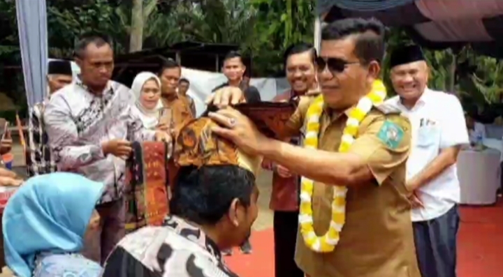 Bupati Simalungun, Radiapoh Hasiholan Sinaga saat menyematkan Gotong atau penutup kepala laki laki orang Simalungun
