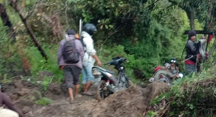 Sejumlah warga berupaya mengevakuasi material longsor yang menghambat kelancaran berlalulintas