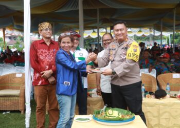 Kapolres Simalungun menyerahkan potongan nasi tumpeng kepada salah seorang pengurus buruh pada peringatan Hari Buruh Internasional di Kabupaten Simalungun.( Nawasenanews/ Ist)