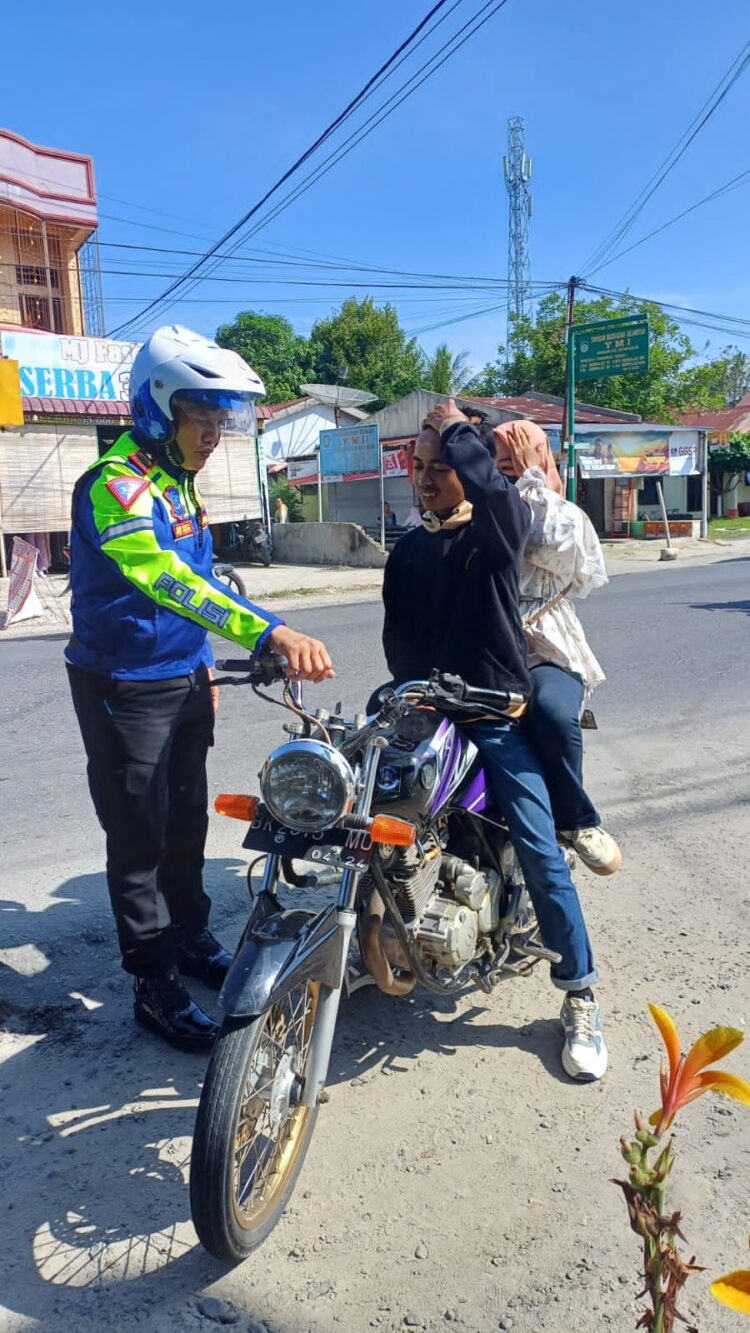 Kasat Lantas Polres Simalungun Iptu Joni Sinaga memberikan teguran dan tilang kepada dua sejoli karena berkendara sepeda motor tetapi tidak mengenakan helm.( Nawasenanews/ Ist)